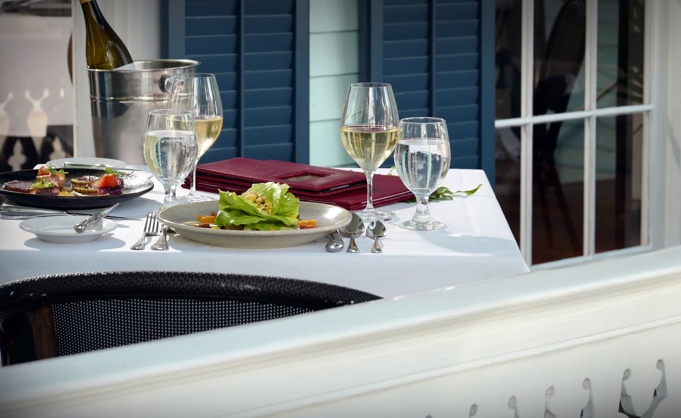 2 glasses of white wine and 2 salads on a patio table at Marquesa