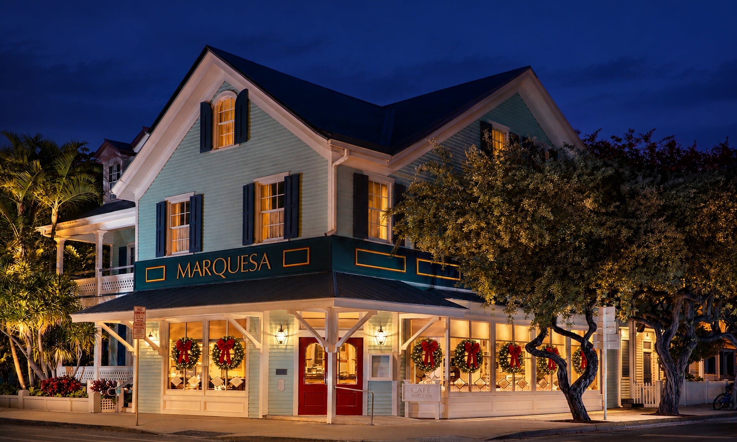 Café Marquesa at The Marquesa Hotel in Key West, Florida, glowing at night with red-bow holiday wreaths